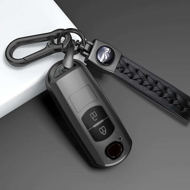 A close-up of a black TPU car key cover attached to a keyring, resting on a gray surface.