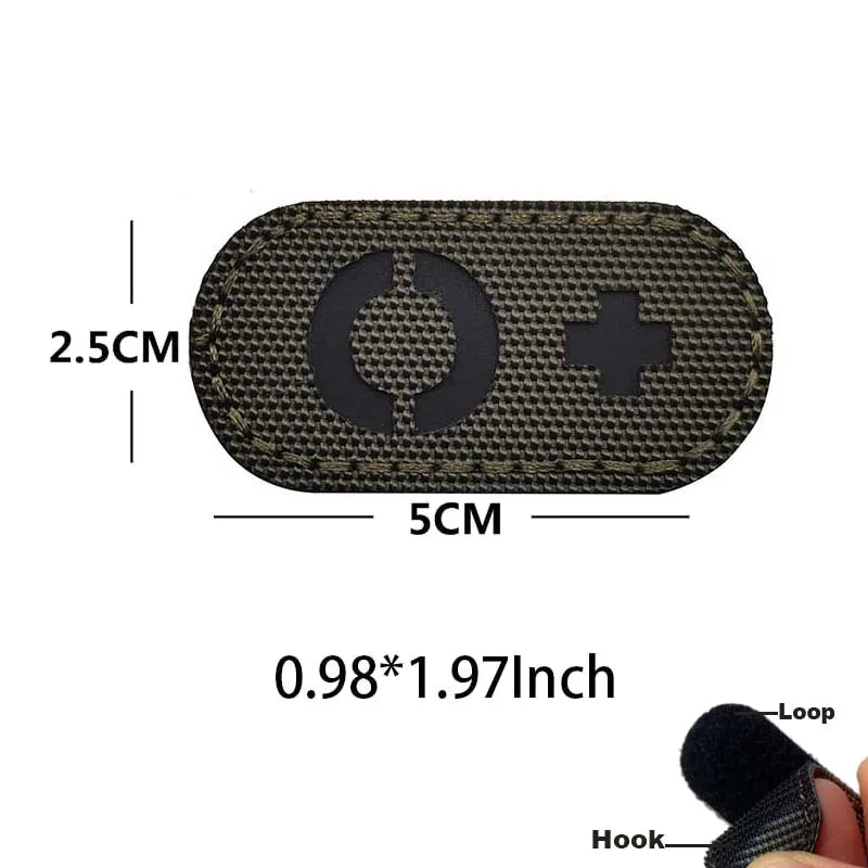 A rectangular, dark tactical patch with a circular design and a plus sign, featuring a hook and loop backing.
