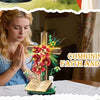A woman prays with her hands folded in front of a floral cross and an open book on a table.