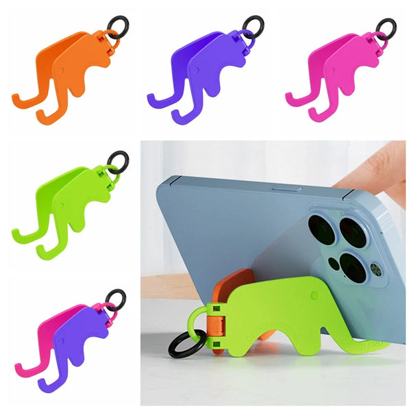 Un juego de soportes plegables para teléfono con forma de elefante en naranja, morado, rosa y verde, junto a un smartphone.