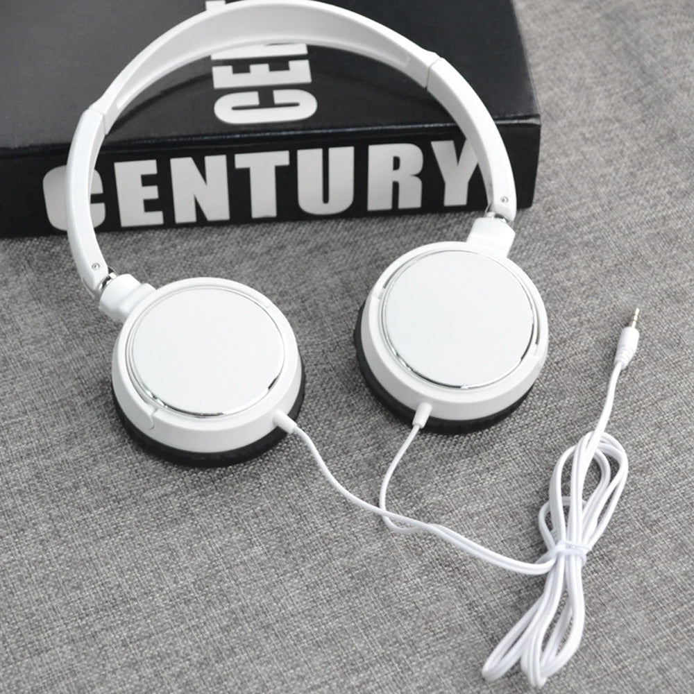 White foldable stereo headphones with a black case and white cord resting on a gray surface.