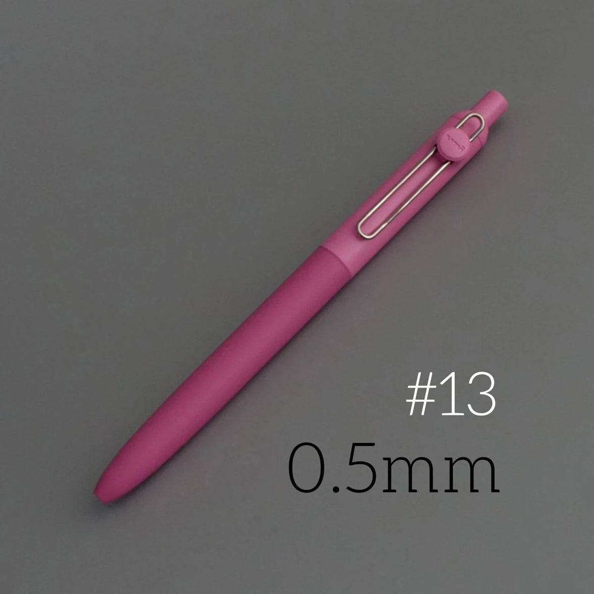 A pink Uni ZENTO quick-dry gel pen with a silver tip, shown diagonally on a gray background.