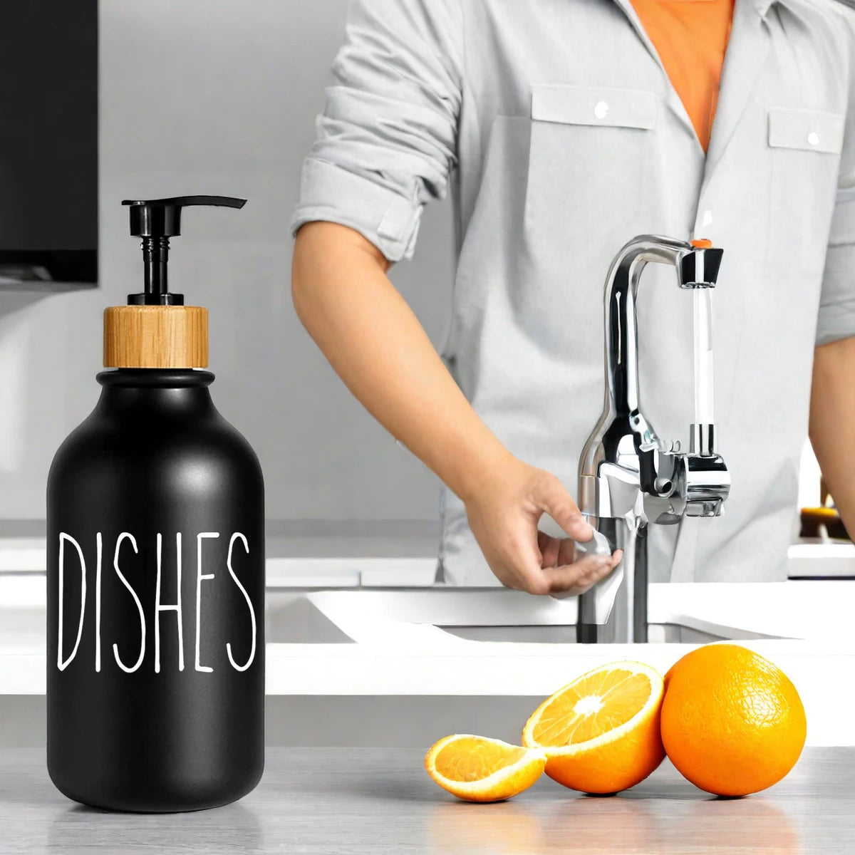 Black bamboo pump dispenser bottle next to a kitchen sink with an orange visible.