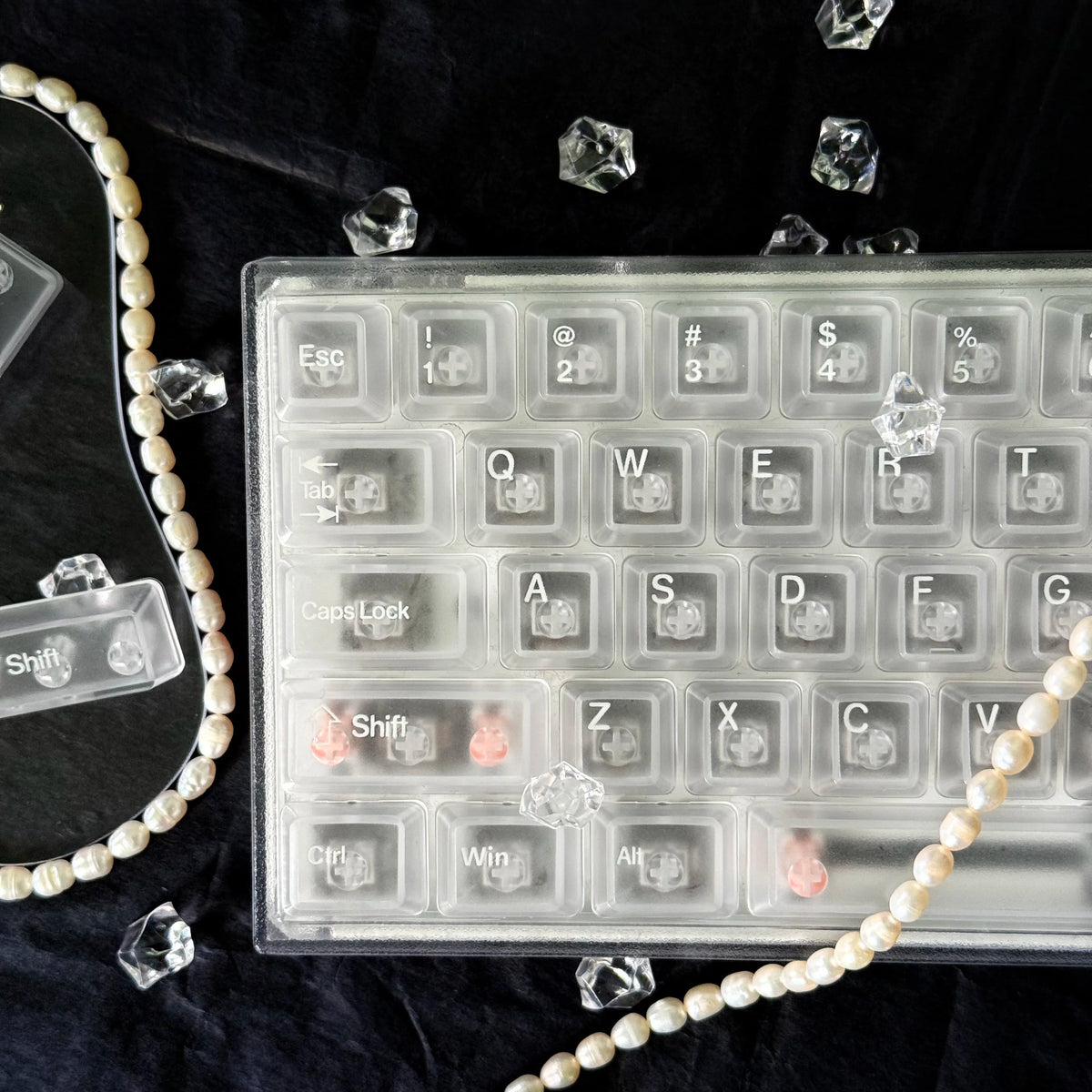 Translucent PC keycaps for mechanical keyboards displayed on a black surface with scattered ice shards.