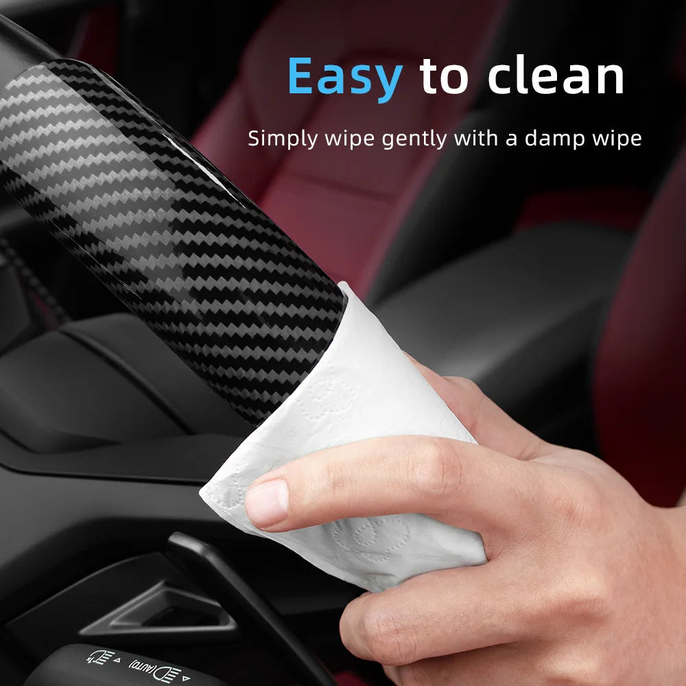 A hand wipes a carbon fiber texture steering wheel cover with a damp wipe for easy cleaning.