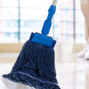 A blue heavy-duty cotton string mop head replacement attached to a white handle, shown in a bright indoor setting.