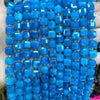 A close-up of strands of bright blue natural stone square faceted beads for jewelry making