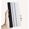 A hand holds a white vinyl applicator tool with black grip and multiple silver blades.