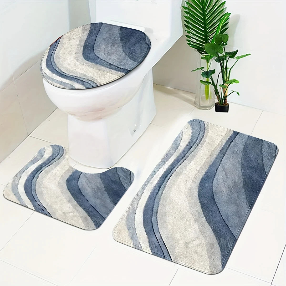 A set of three gray and blue striped bathroom rugs, including a U-shaped toilet mat and cover, placed on a white floor.