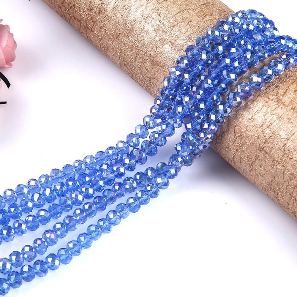 Blue faceted crystal glass spacer beads strung together on a golden brown paper roll.