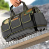 A hand is holding a heavy-duty camouflage tool bag with a reinforced base, shown resting on a wooden surface.
