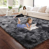 A young girl lies on a dark gray plush carpet in a bright living room with a woman and a dog nearby.