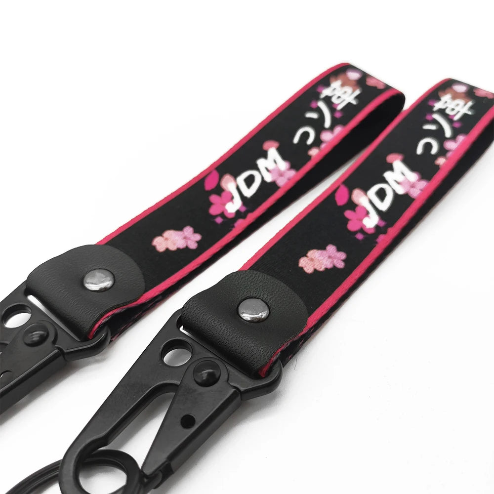 Black strap with pink floral print and JDM text, featuring a metal clasp.
