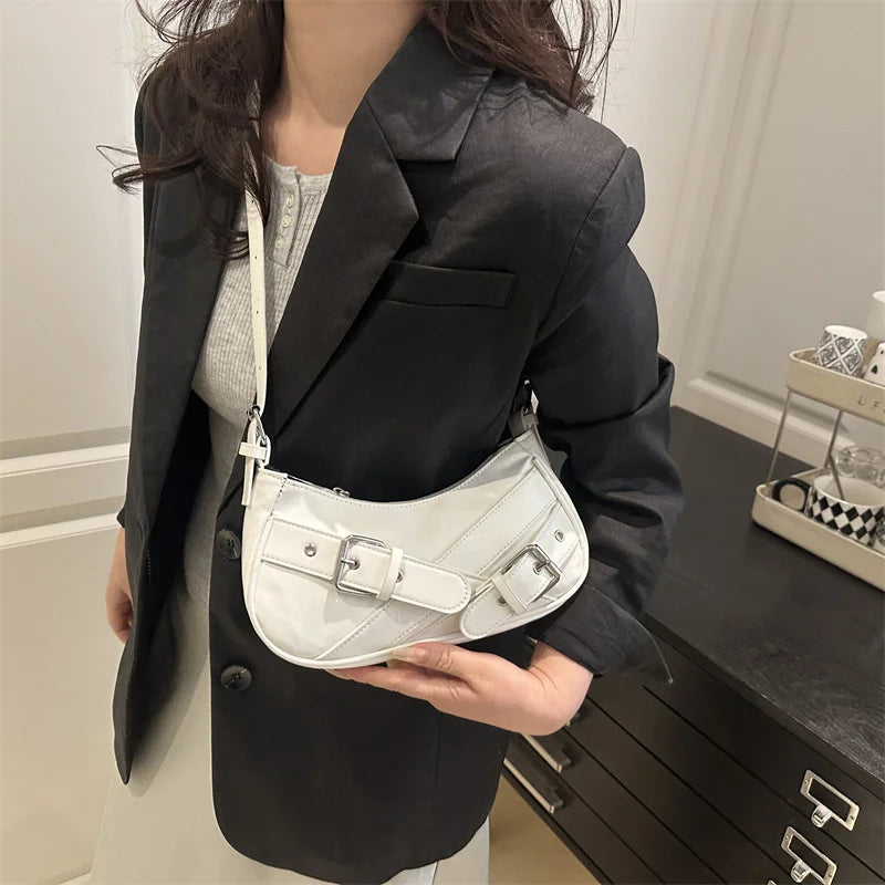 A woman holds a white Y2K vintage PU leather crossbody bag against a black blazer.