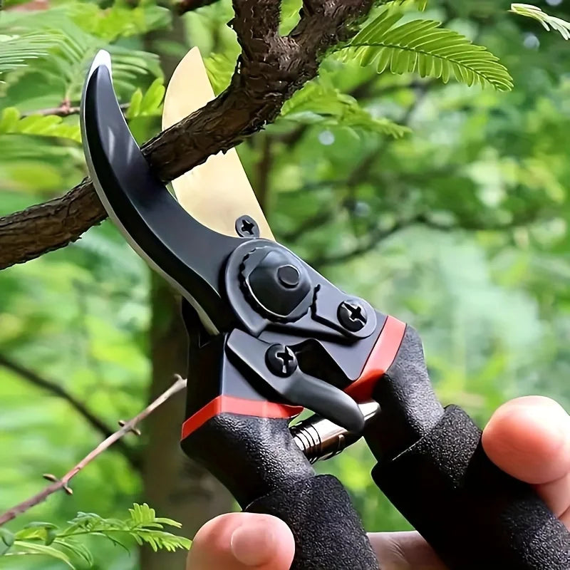Close-up of black garden pruning shears with a light blade and a black non-slip handle, set against green foliage.