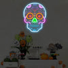 A glowing neon light shaped like a skull with colorful internal details hangs on a wall above a table display.