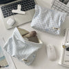 A light blue and white striped makeup bag is shown next to a laptop, a wireless mouse, and a white wireless mouse.