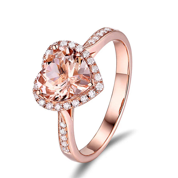 A rose gold heart-shaped ring featuring a central pink gemstone surrounded by small clear stones.
