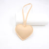 A light peach heart-shaped PU leather keychain with a cotton charm hanging from a loop.
