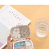 A hand holds an open weekly pill organizer with eight compartments, showing various colored pills and a clear glass of water.