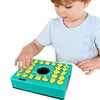 A young child is playing a green puzzle board game with yellow pieces on a white background.