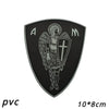 A black shield patch featuring the letters A and M, with an archangel design and a cross emblem.
