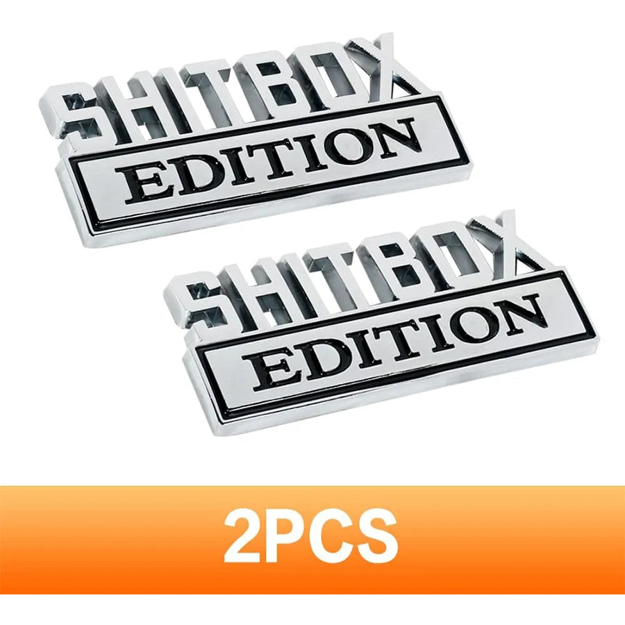 Ein Satz aus zwei silbernen Metallabzeichen mit dem Text SHITBOX EDITION