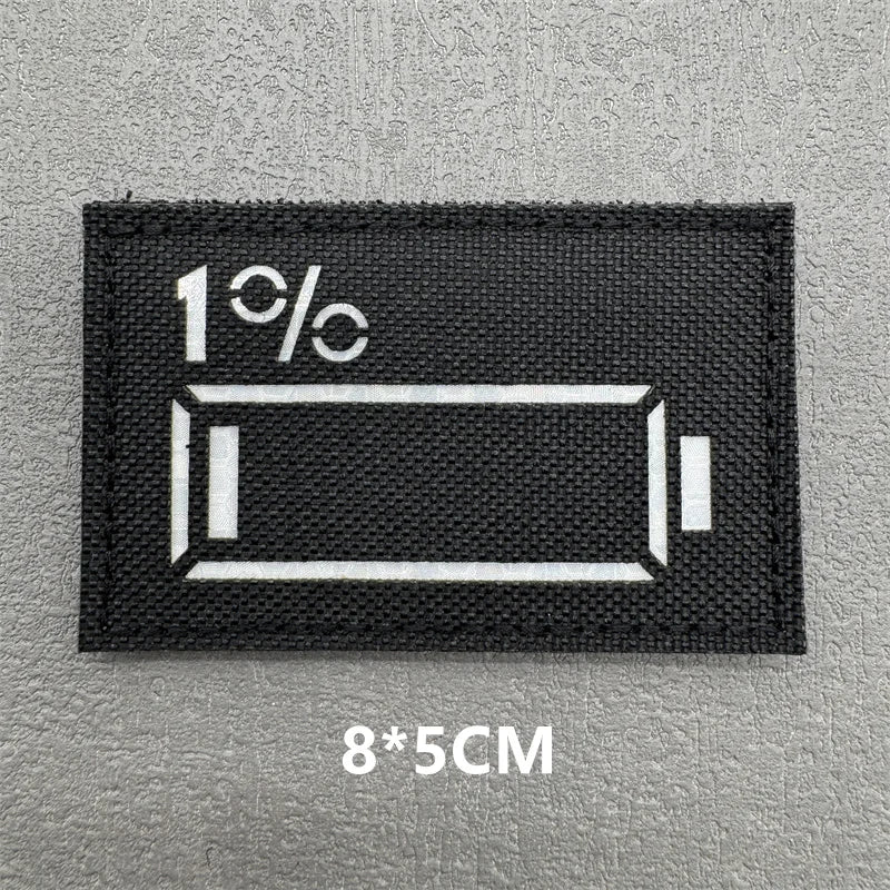 Black rectangular patch with white text 1% and a horizontal bar design on a gray background