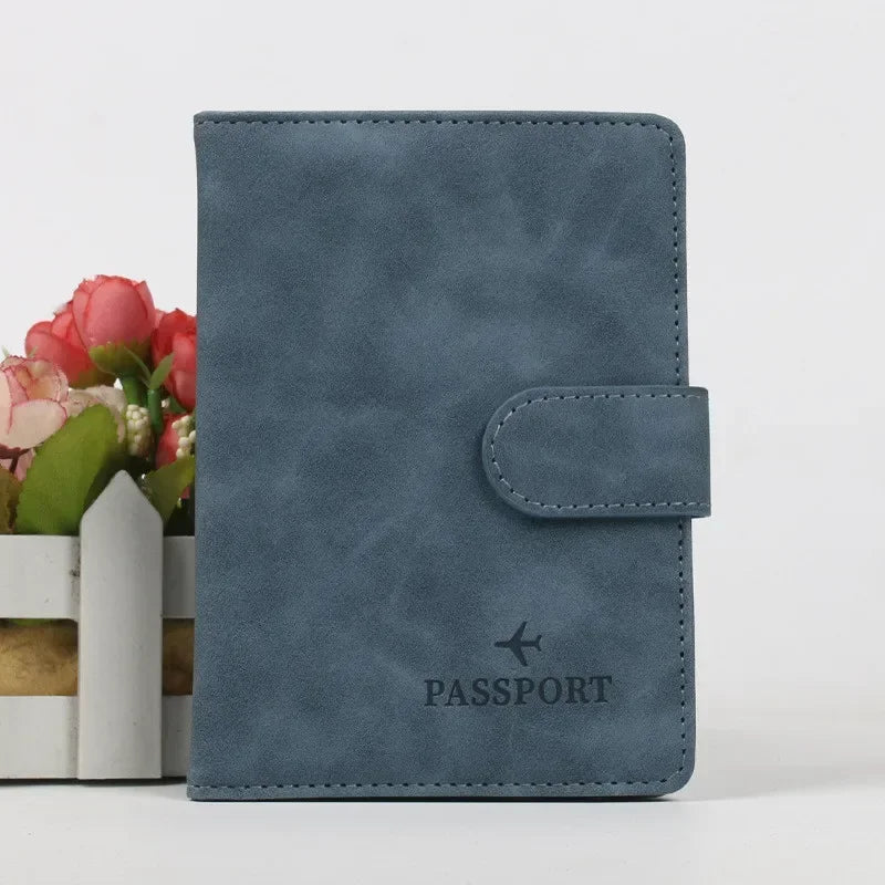 Porte-passeport en cuir bleu foncé avec rabat, posé à côté d'un petit arrangement de fleurs roses.