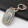 A light blue Honda key fob cover with a gold-tone chain attached, resting on a black surface.