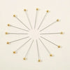 A set of 100 precision quilting pins with gold-colored heads arranged radially on a white background.