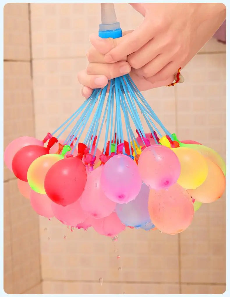 A hand is squeezing a cluster of blue water balloons, with many other colored balloons hanging down.