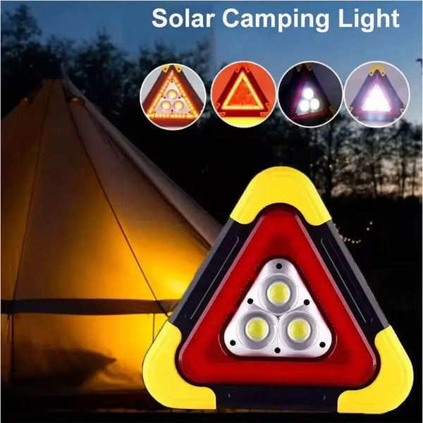 A triangular solar camping light with three LED lights and a flashlight illuminating a tent in the dark.