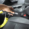 Une main utilise une sangle jaune pour fixer un loquet de volant universel à un ancre de ceinture dans l'habitacle d'une voit