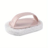 A pink magic sponge scrubber with a long handle rests on a white scouring pad.