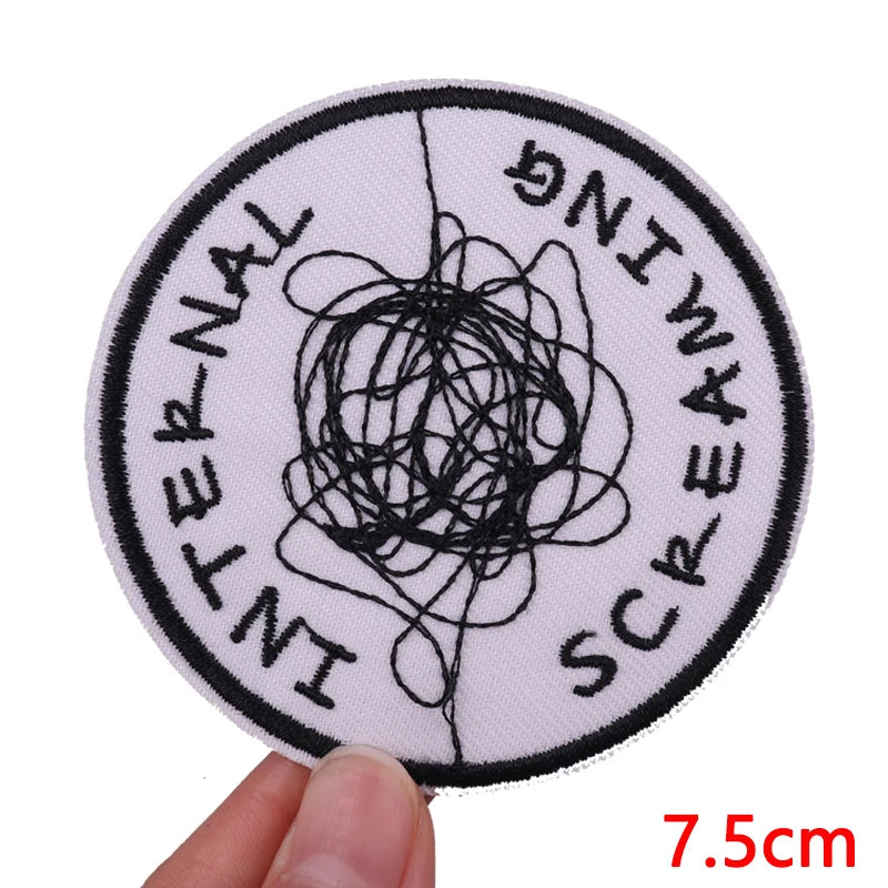 A round white patch with black embroidery spelling out INTERNATIONAL SCREAMING