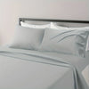 A close-up of a bed with white linens and a gray duvet, featuring a modern metal headboard.