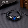 A black leather wrap bracelet featuring a glowing blue and purple celestial charm.