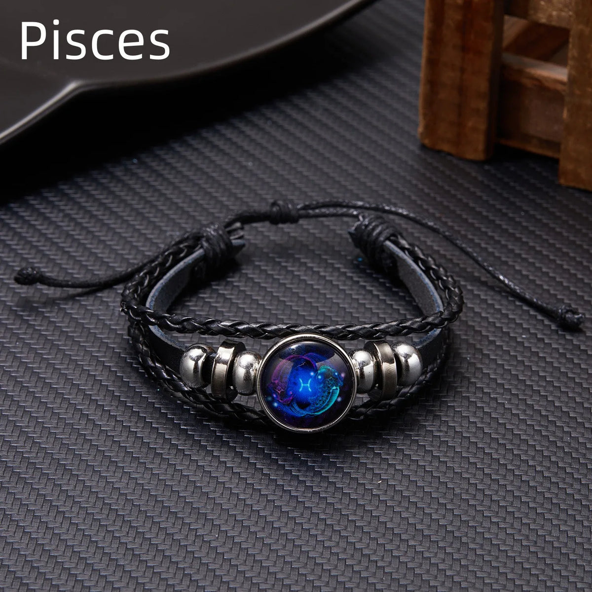 A black leather wrap bracelet featuring a glowing blue and purple celestial charm.