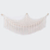 A cream-colored bohemian plush toy storage hammock with fringe details.