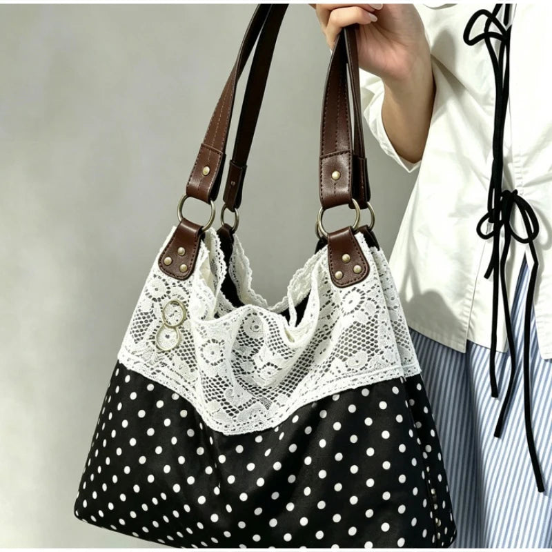 Un gros plan d'un sac à main patchwork à pois noir et blanc avec bordure en dentelle blanche, tenu par une main.