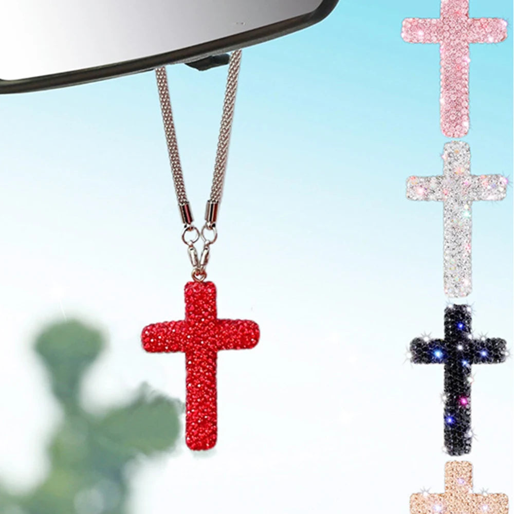 A red rhinestone cross pendant hanging from a silver chain, displayed against a light blue background.