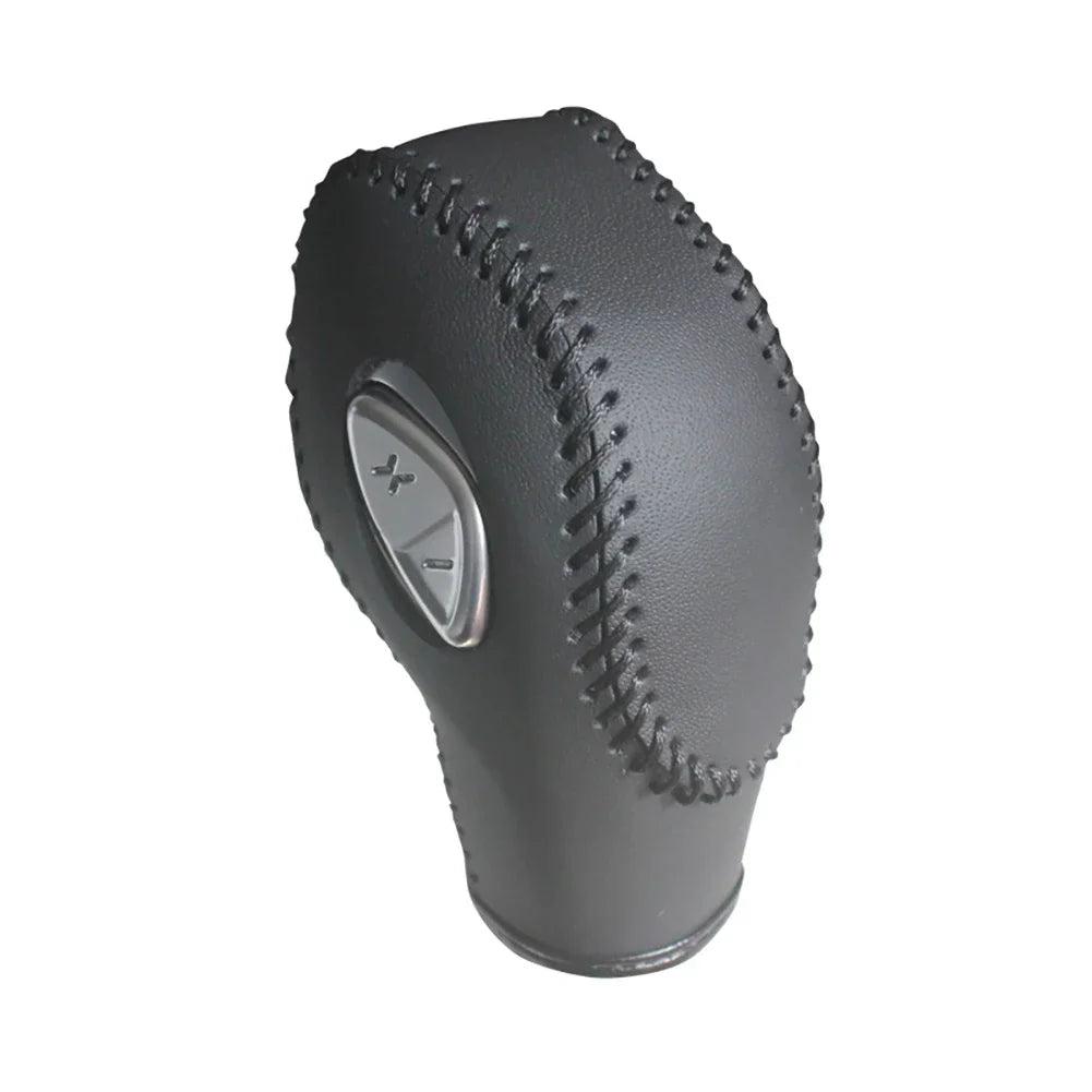 A dark gray carbon fiber gear shift knob cover for a vehicle.
