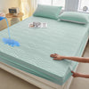 A teal fitted mattress protector is shown on a bed, with a hand adjusting the fabric.