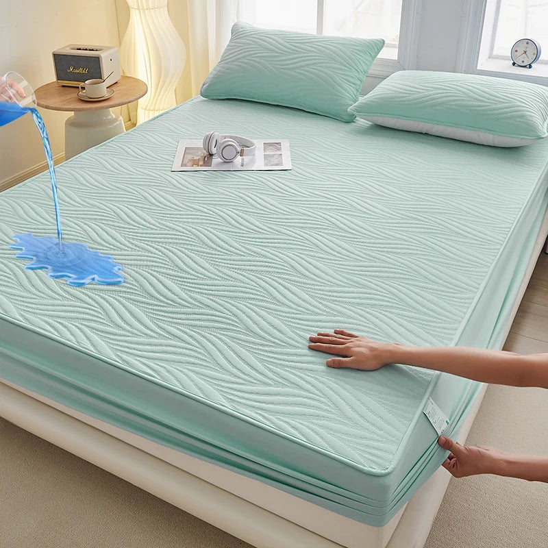 A teal fitted mattress protector is shown on a bed, with a hand adjusting the fabric.