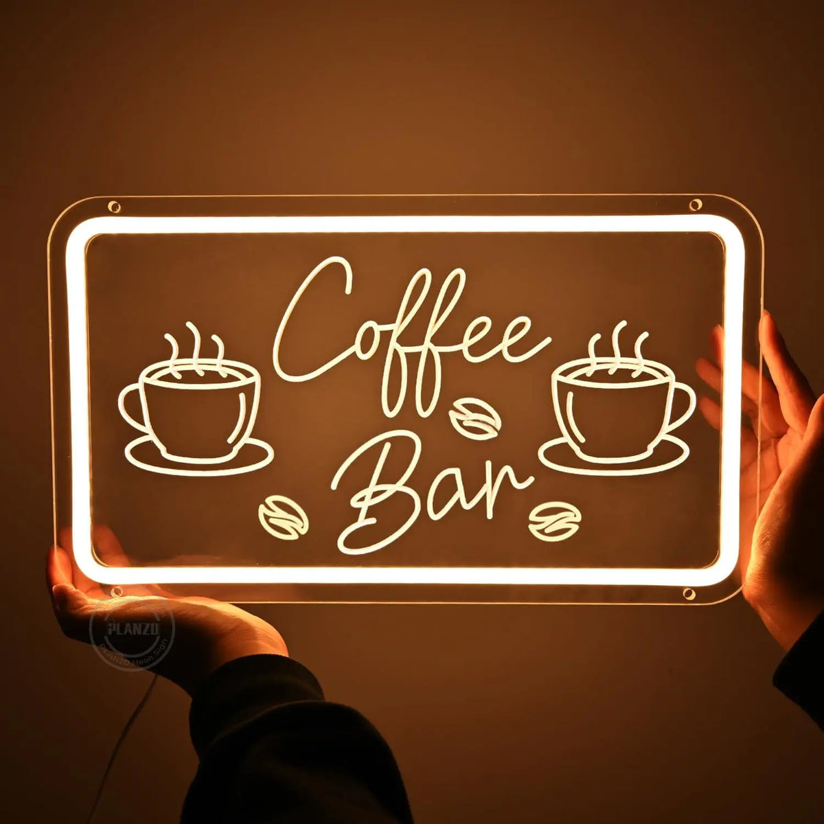 A hand holds a glowing neon sign shaped like coffee beans and a bar, illuminating the text Coffee Bar.