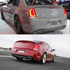 A red Chrysler 300 is driving on a road, showing the rear bumper reflector light covers.