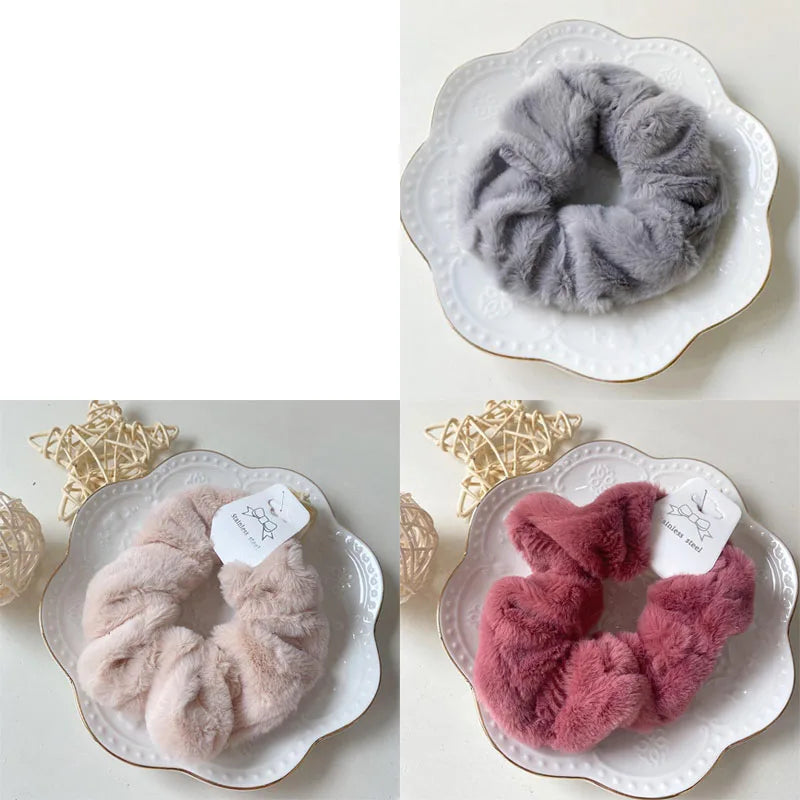 A close-up of a gray and pink plush coil hair tie displayed on a white plate.
