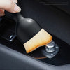 A black soft-bristled cleaning brush is shown being used to clean a car vent or crevice.