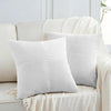 A set of two white retro corduroy patchwork throw pillow covers displayed on a light-colored sofa.